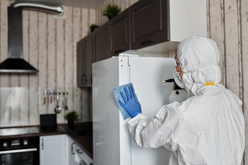 Hazmat-suited worker decontaminating kitchen