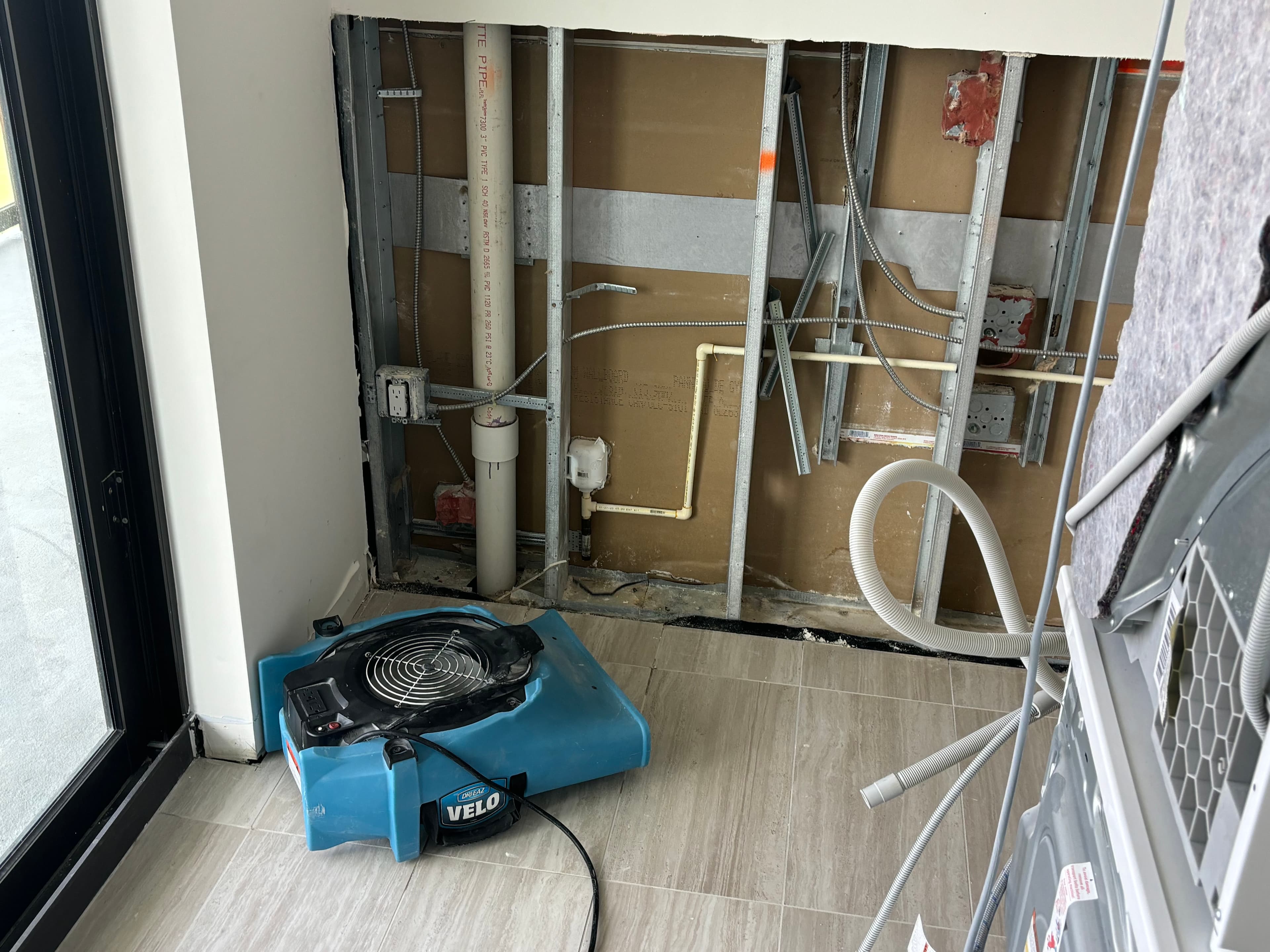 Opened wall with air mover running during water damage restoration